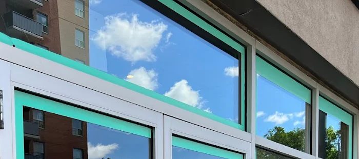 Clean storefront glass reflecting a blue sky and clouds