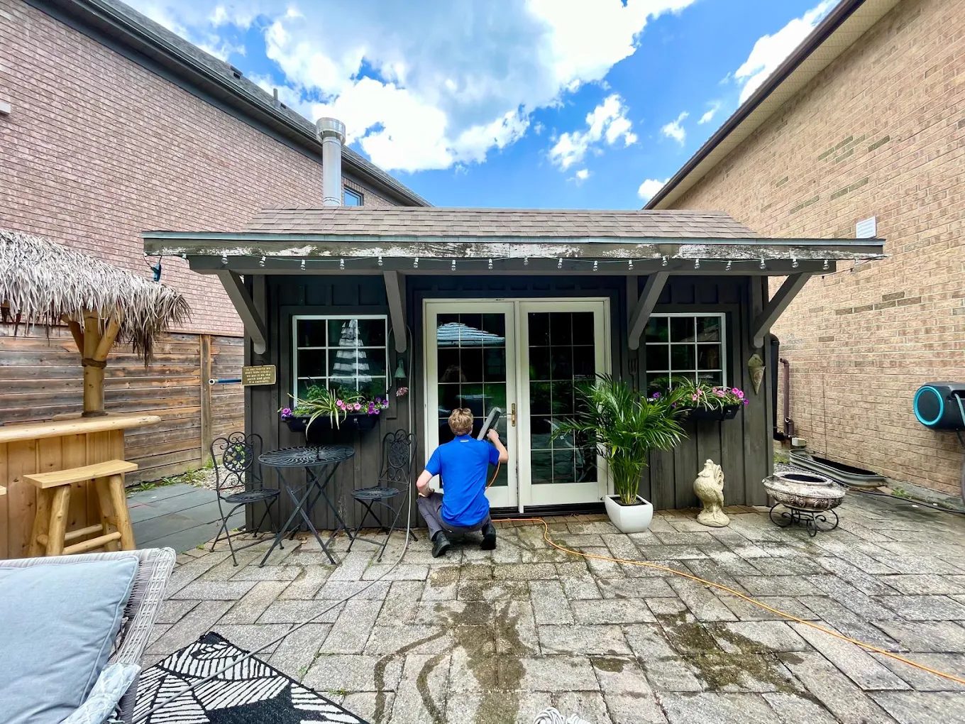 Clearpane Co. window cleaner in a blue polo cleaning the glass doors of a garden studio